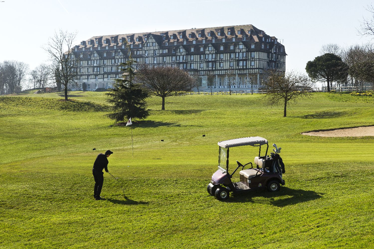 golf-expedition-golf-reizen-frankrijk-regio-normandië-hotel-du-golf-barriere-golfer-op-golfbaan-met-hotel-op-achtergrond.jpg